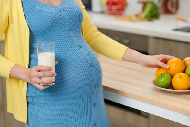 韩国人年轻的孕妇拿着一杯牛奶在餐桌旁 厨房里有食物女性孕妇亚洲人