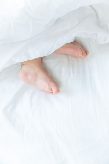 复制空间宝宝用脚睡在白色的床上放松手美丽