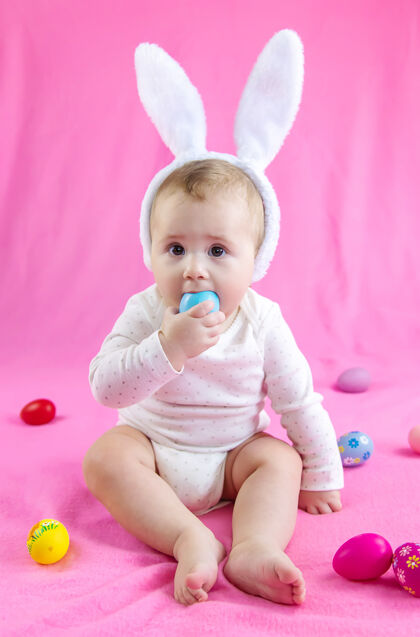 孩子穿得像兔子的宝宝 带着复活节彩蛋过复活节服装抱着老