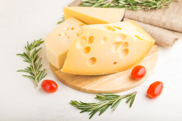 板各种类型的奶酪与迷迭香和西红柿在木板上的白色木质表面和亚麻织物奶酪亚麻布番茄