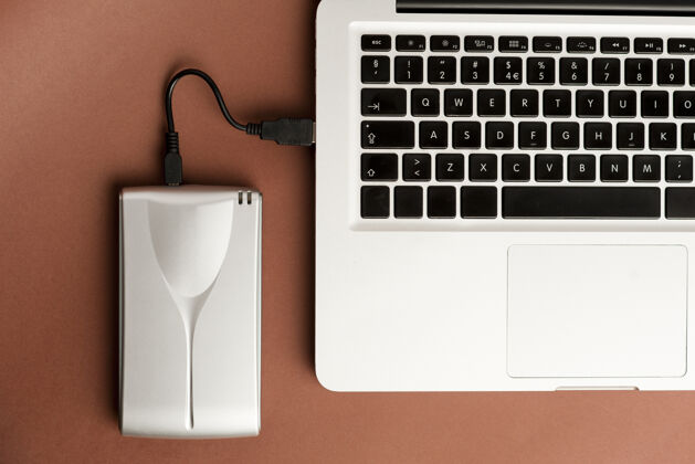 外部铝制外置硬盘 带u电缆 连接到棕色办公桌面上的笔记本电脑上硬办公桌手机