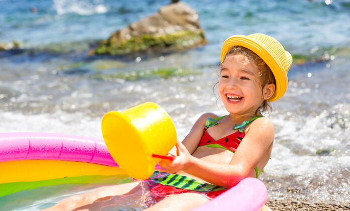 水戴着黄色草帽的女孩在沙滩上的充气游泳池里玩风 水和饮水机酒店海洋浴缸