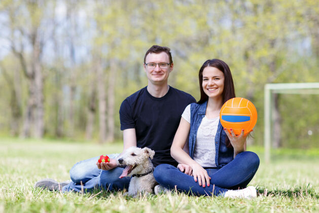 浪漫快乐的年轻夫妇和他们的狗在公园里团结男人微笑