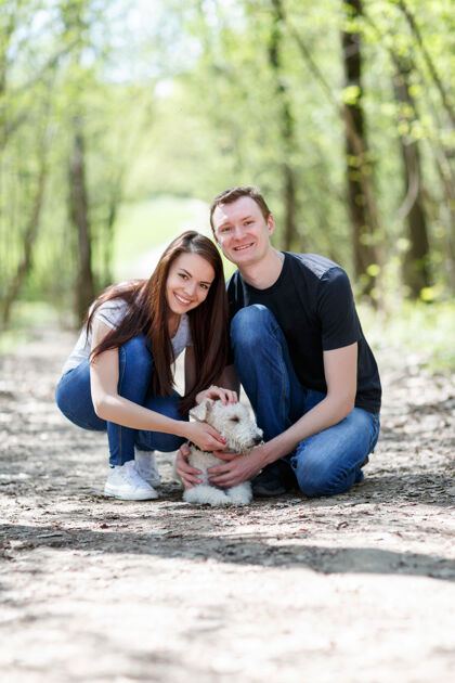 爱情快乐的年轻夫妇和他们的狗在公园里男朋友家庭父母
