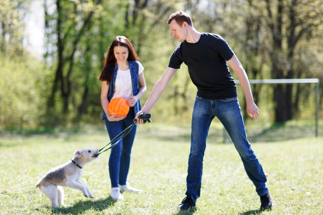 狗快乐的年轻夫妇和他们的狗在公园里家庭在一起父母