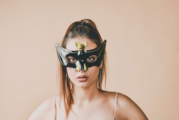 女人戴蝙蝠面具参加化妆舞会或万圣节派对的年轻女子女性人面具