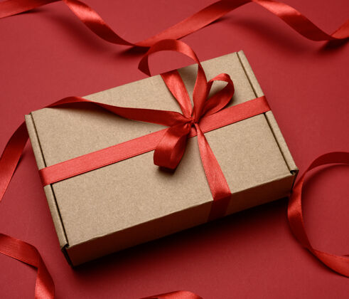 丝绸长方形的棕色纸板箱 上面系着一条红色的丝带纸庆典礼物
