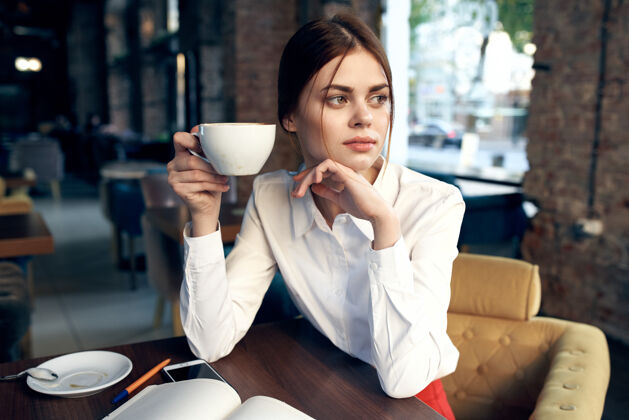 女性一个手里拿着杯子的美女坐在咖啡馆的桌子旁看书成年人女孩杯子