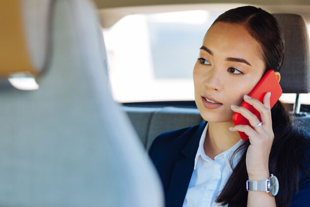 进步远程通讯聪明的年轻女子一边通话一边把电话放在耳边忙碌通话亚洲人
