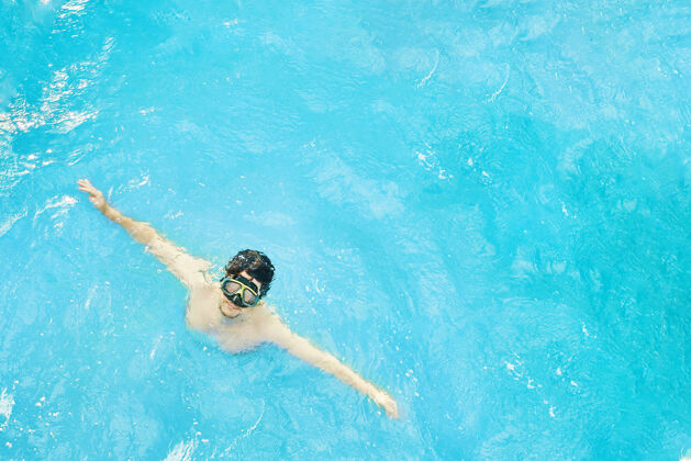 水下一个戴着水下面具的人在度假的时候从海里潜水出来 一个伸出双臂休息的家伙潜水员休息男性