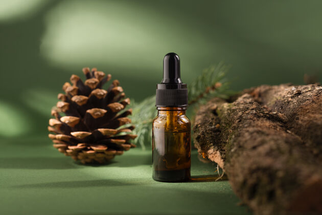 木材化妆瓶上有滴管的木质树皮和苔藓松树精油的深绿色背景治疗芳香疗法治疗