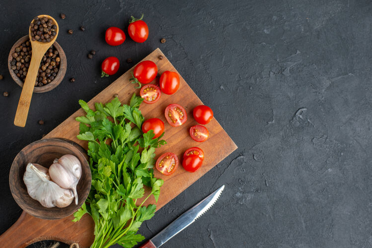 刀特写镜头绿色捆绑新鲜的全切西红柿大蒜在木制砧板刀胡椒在黑色的痛苦的表面番茄沙拉食物