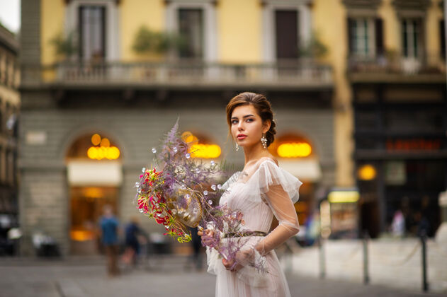 城市一个新娘穿着婚纱 手里拿着威尼斯面具florence.italy.!城市 女人 微笑 新娘 意大利 城市景观 历史 花束 年轻 婚纱 快乐 古城 佛罗伦萨 威尼斯面具 手 美丽的面具 年轻的模特 花艺