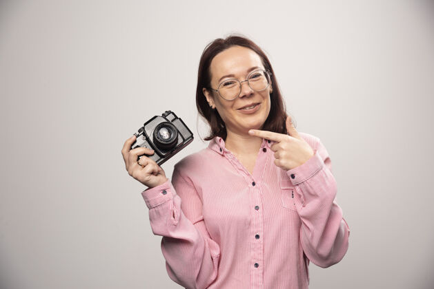 拍摄女人在一张高质量的白色照片上展示相机可爱漂亮摄影师