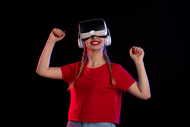 年轻女性在黑暗科技游戏d上 年轻女性戴着耳机玩vr的正面图虚拟现实姿势耳机
