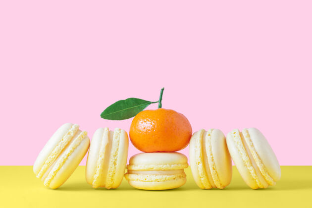 橙色黄色的法国杏仁饼配柠檬奶油 黄色和粉色的背景很可爱复制空间法国水果