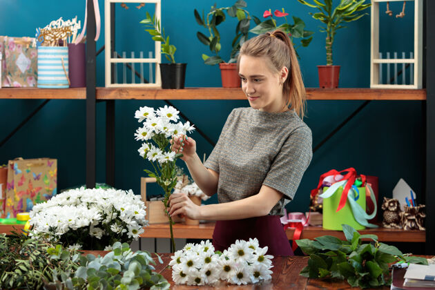 业主花匠做了一个花束一个年轻的成年女孩选择白菊花作为花束成人花店雏菊