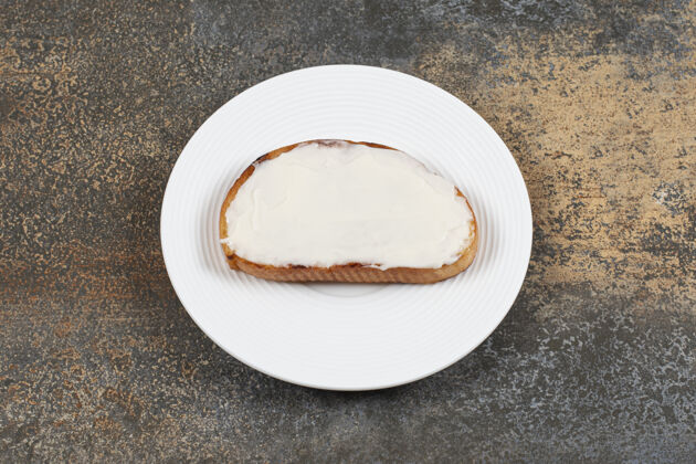 面包在白色盘子上放一片带酸奶油的烤面包片美味奶制品酸奶油
