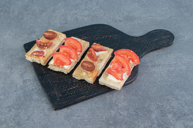 蔬菜一块黑色的木板 上面放着西红柿和酥脆的烤面包木头切片谷类