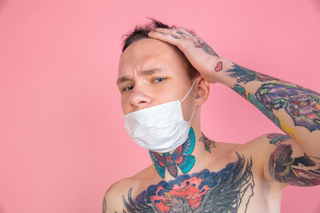 流行戴着面具粉色背景上的年轻怪人画像复制空间粉红纹身