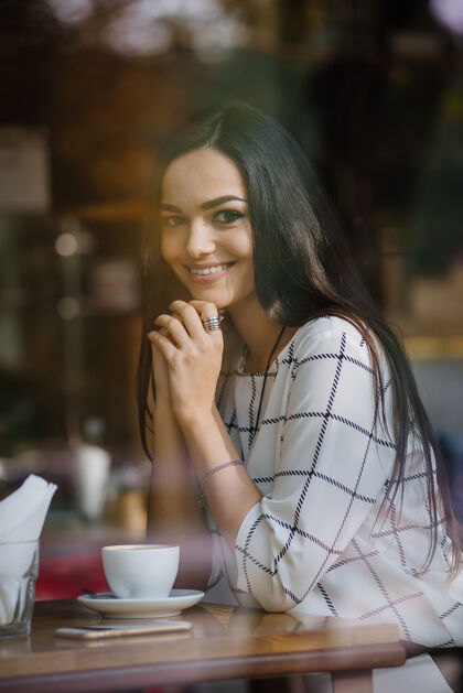 杯子年轻漂亮的黑发女郎坐在咖啡馆里喝茶咖啡黑发女人