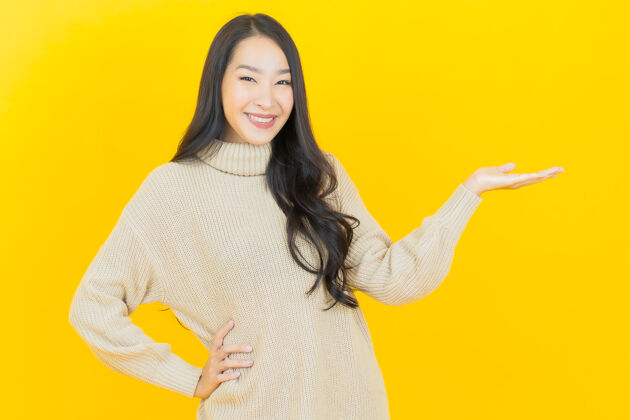 生动美丽的亚洲年轻女子在黄色的墙上微笑明亮脸多彩