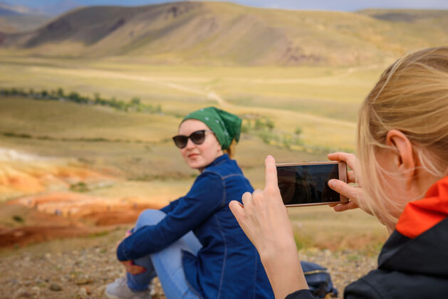 成人女游客用智能手机在一个美丽的有利位置 特写镜头 选择性聚焦拍摄女友的照片照片游客拍照