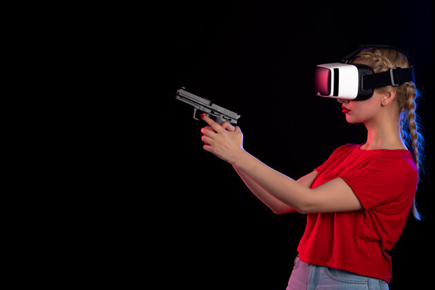 玩前视图漂亮的女性玩虚拟现实与枪上的黑暗代理技术视觉发挥广播技术枪