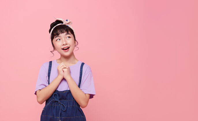 小学生快乐的亚洲小女孩被隔离在粉红色的复制空间墙上微笑脸人