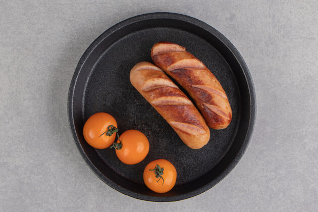 蔬菜烤香肠和西红柿放在黑盘子里美味美味香肠
