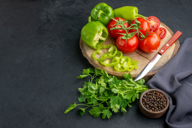 生菜新鲜西红柿和青椒在木板上的正面图黑色表面上的绿色捆绑素食营养包