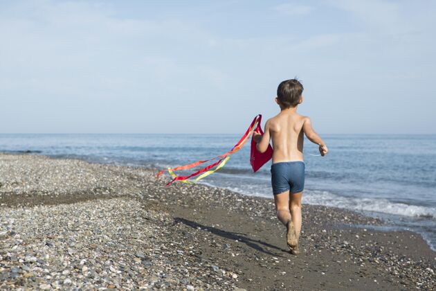 孩子在沙滩上玩风筝的全镜头小孩海边放松全镜头