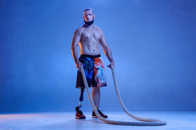 霓虹灯专业男子运动员与腿假肢训练与绳索在霓虹灯腿部保健训练