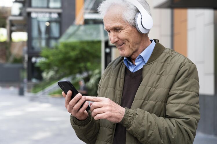 户外笑眯眯的城里老人戴着耳机听音乐老年人老年人音乐