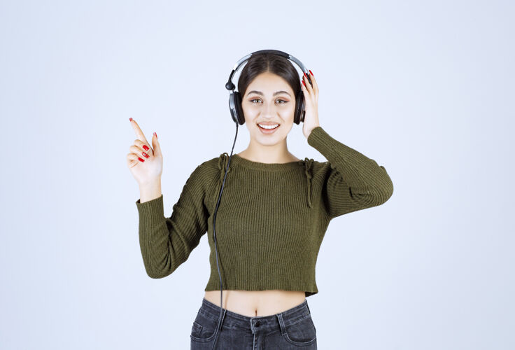 耳机戴着耳机听音乐指点的少女画像情感时尚姿势