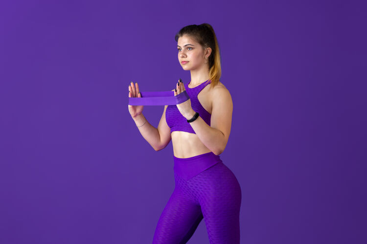 女性强壮美丽的年轻女运动员在练习 单色紫色肖像运动型白种人适合模型与弹性健身 健康的生活方式 美丽和行动的概念强壮人运动员