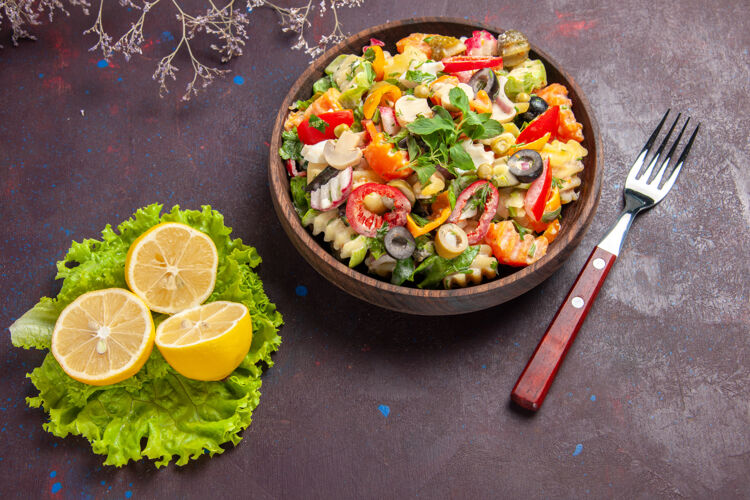 午餐俯瞰美味的蔬菜沙拉与柠檬片和绿色沙拉对黑暗的背景沙拉餐健康饮食胡椒美食蔬菜