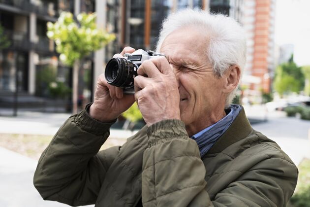 老年人时尚的老男人在城市里用相机拍照男人老年人城市