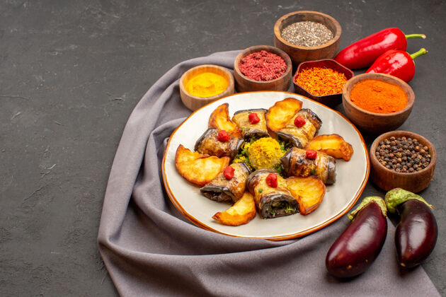 土豆前视图茄子卷熟菜与烤土豆和调味料在黑暗的空间一餐调味品午餐