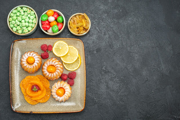 晚餐俯瞰图美味的小蛋糕柠檬片橘子和糖果在黑暗的背景茶水果饼干甜饼干派派盘子美味