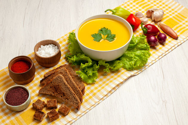 生菜前视图美味的南瓜汤与不同的调味品和面包在白色空间前面沙拉盘子