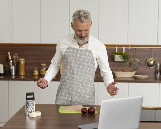 室内家里的老人在厨房用笔记本电脑上烹饪课水平厨房男性