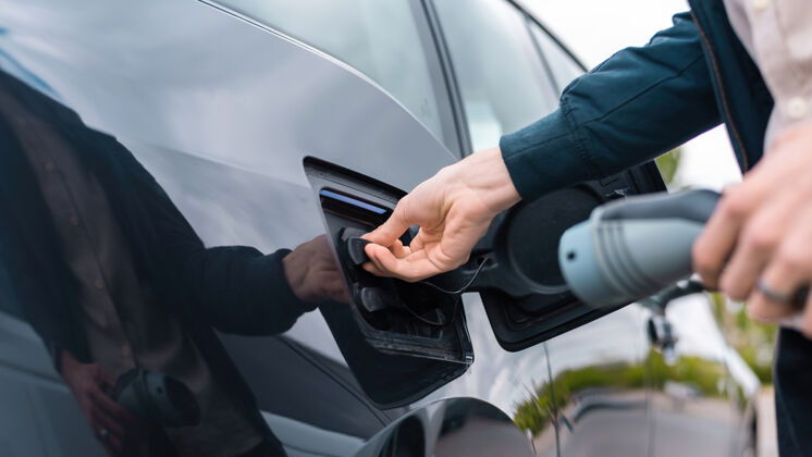 环境男子打开汽车充电插座和手持充电器在充电站驾驶充电器未来