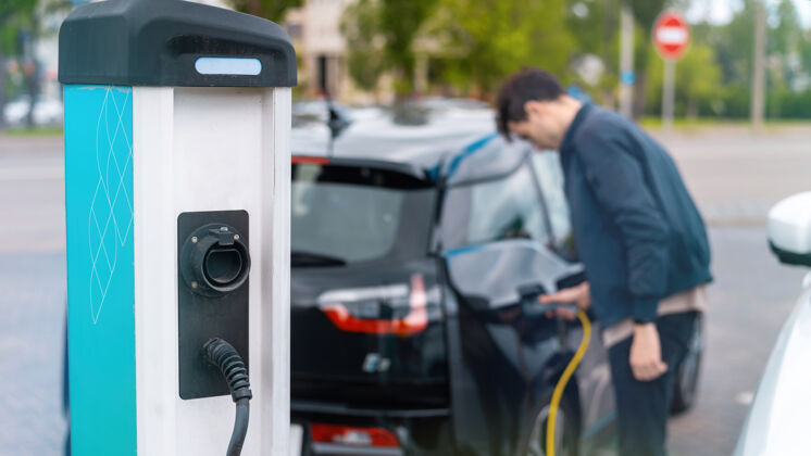 充电器在充电站把充电器插进电动车的人电动车科技能源