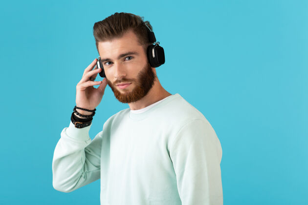 无线时尚迷人的年轻留胡子的男人在无线耳机上听音乐的肖像现代风格自信的心情时髦耳机城市