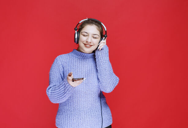 播放列表戴着耳机的女孩在她的智能手机上放音乐 享受着它成人人类聪明