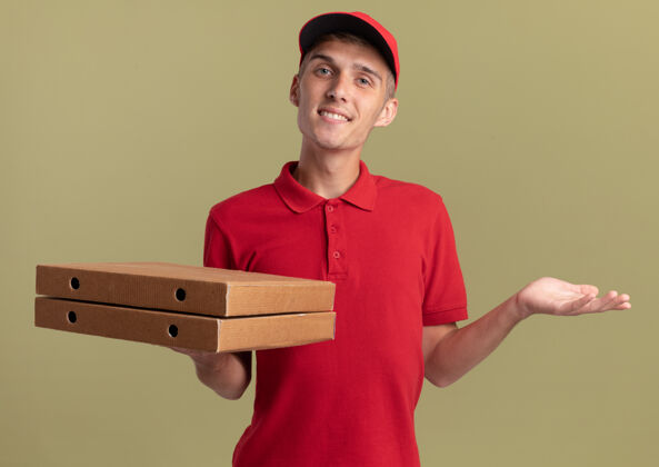 送货微笑的年轻金发送货男孩拿着比萨饼盒 手一直张开男孩打开持有