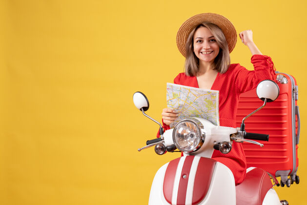 年轻女士前视图：骑着轻便摩托车的年轻女士 手拿红色手提箱 地图上显示手臂肌肉旅游表演乐趣