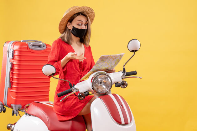 坐着前视图穿着红色衣服的年轻女士坐在轻便摩托车上看地图红色地图度假