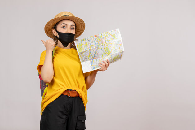 人正面图年轻的旅行者背着背包举着地图指向后面流行病旅游旅游